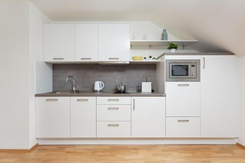 a white kitchen with white cabinets and a microwave at Cosy New Town Attic Studio in Prague