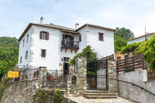 a white house with a stone wall at Archontiko Panagoula in Portaria