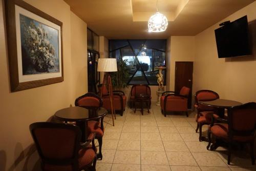 una sala de espera con mesas, sillas y TV en Hotel Santa Maria en Lima