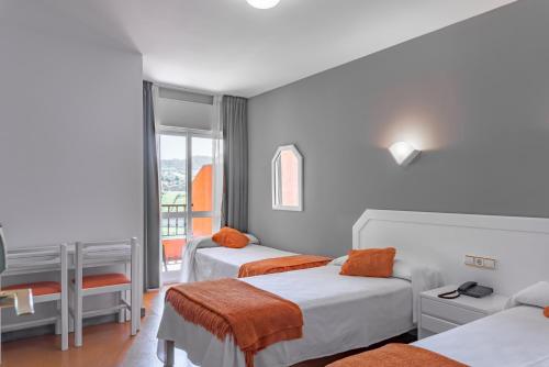 レヴォルタにあるHotel Los Naranjosのベッド2台と窓が備わるホテルルームです。