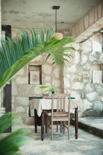 a table in a stone room with a table and a chair at Coqui Coqui Papholchac Coba Residence & Spa in Cobá