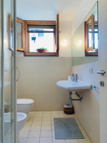 a bathroom with a sink and a toilet and a window at Arco 37 in Alghero