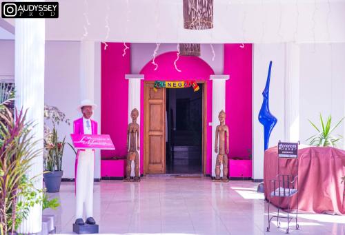 a man standing at a podium in front of a pink building at La maison de celine in Dakar