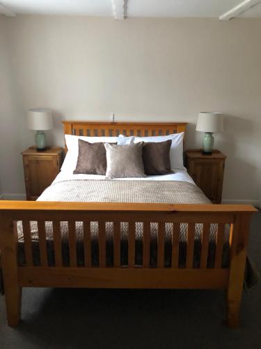 a bedroom with a wooden bed with two lamps at The George at Nunney in Frome