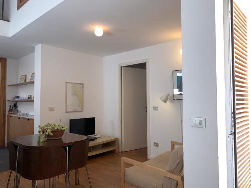 Una sala de estar blanca con una mesa y un televisor. en Arco 37, en Alghero