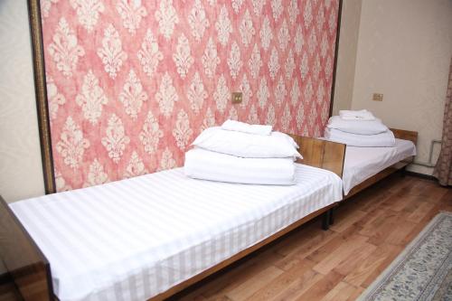 two beds in a room with white sheets on them at MEDI Guest House in Osh