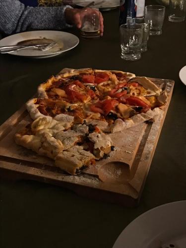 une pizza sur une planche de découpe en bois sur une table dans l'établissement Le Mazacote de Florisol, à Les Cotes de Corps