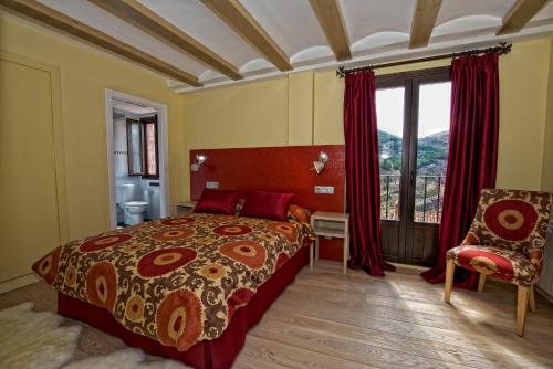 um quarto com uma cama, uma cadeira e uma janela em Hotel Albanuracín em Albarracín
