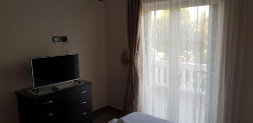 a bedroom with a television on a dresser next to a window at Villa Anastasia Ksamil in Ksamil
