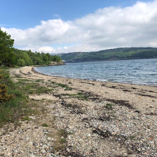 a beach with a body of water and trees at Swift Bordeaux Sea View 15 in Dunoon