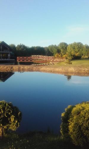 a pond with a wooden fence next to a building at Domek nad stawem in Działdowo