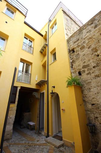 a yellow building with a stone wall next to it at Khalisah in Palermo