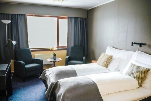 um quarto de hotel com uma cama e duas cadeiras e uma janela em Vågslidtun Hotel em Vågsli