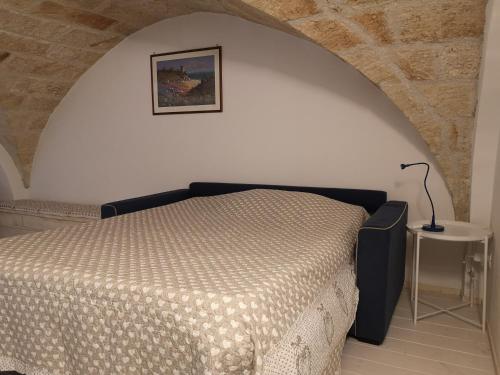 een slaapkamer met een bed en een tafel met een lamp bij Dimora Del Mar in Polignano a Mare
