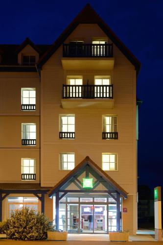 a tall yellow building with a sign in front of it at ibis Styles Deauville Villers Plage in Villers-sur-Mer