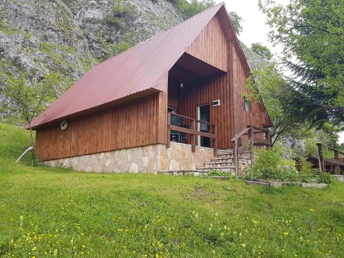 a wooden barn with a red roof in a field at Detached house Milivoje in Pošćenje
