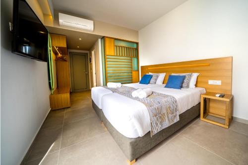 een slaapkamer met een groot bed en een flatscreen-tv bij Adele Beach Hotel in Adelianos Kampos