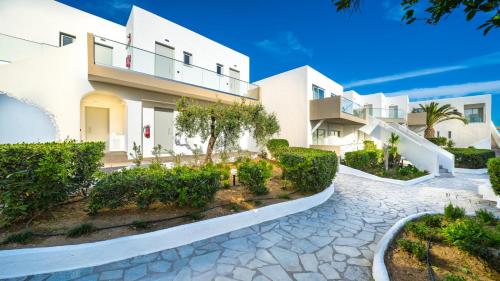a large white building with a cobblestone driveway at Adele Beach Hotel in Adelianos Kampos