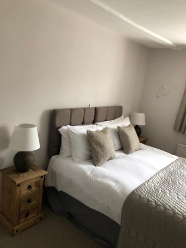 a bedroom with a large bed with white sheets and pillows at The George at Nunney in Frome