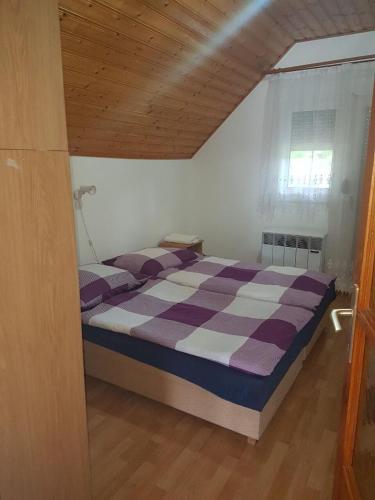 a bedroom with a purple and white bed with a window at Gold Apartment in Harkány