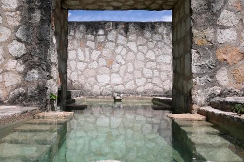 una piscina d'acqua di fronte a un muro di pietra di Coqui Coqui Papholchac Coba Residence & Spa a Cobá