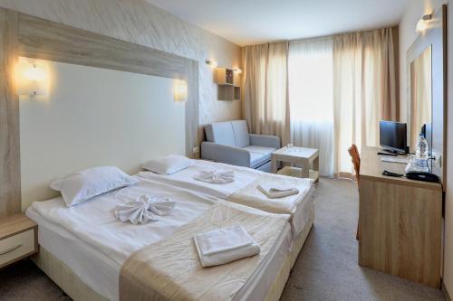 ein Hotelzimmer mit einem großen weißen Bett und einem Schreibtisch in der Unterkunft Paraiso Beach - All Inclusive in Obsor