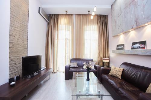 a living room with a leather couch and a television at Langery Residence Central Apartments in Odesa