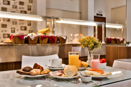 una mesa con platos de comida y bebida para el desayuno en Zallon Hotel Executivo, en Lajeado