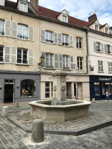 una fuente en medio de una calle con edificios en La bohème - Chambres d’hôtes, en Senlis