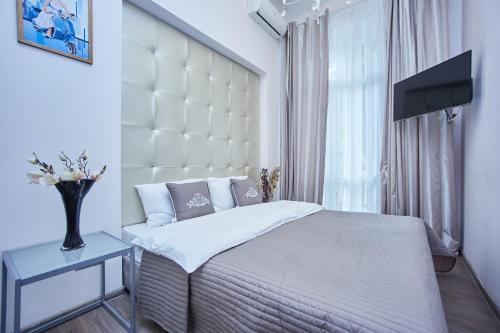 a bedroom with a bed with a large white headboard at Langery Residence Central Apartments in Odesa