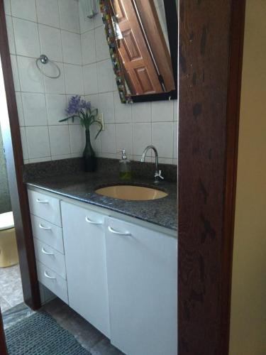 a bathroom with a sink and a vase of flowers at Jeremias Hostel Bar in Vila Velha