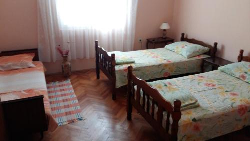 a bedroom with three beds and a window at Apartman Izvor in Vrnjačka Banja