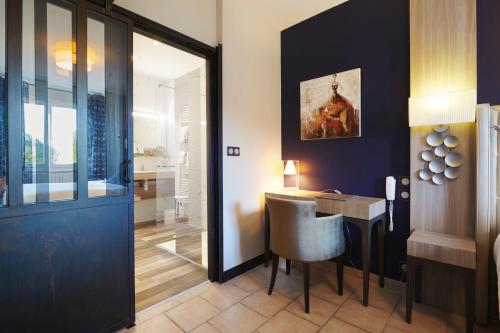 a room with a desk and a table with a chair at Pont du Chalon Hôtel and Restaurant in Margès