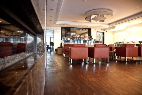 a dining room with red chairs and a bar at Hotel Favor in Düsseldorf