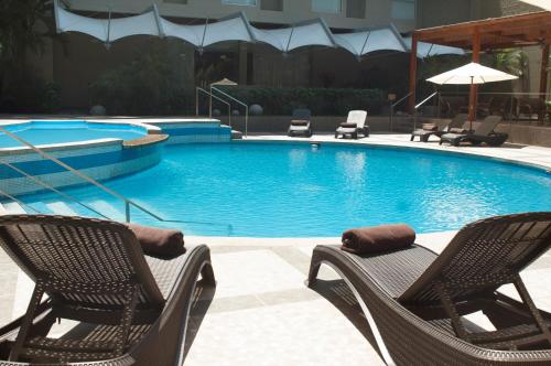 a swimming pool with two chairs at Casa Andina Select Pucallpa in Pucallpa