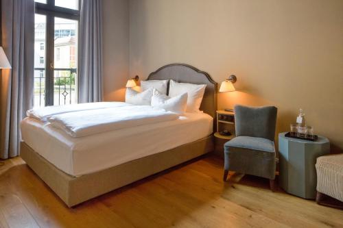 a bedroom with a bed and a chair and a window at Monbijou Hotel in Berlin