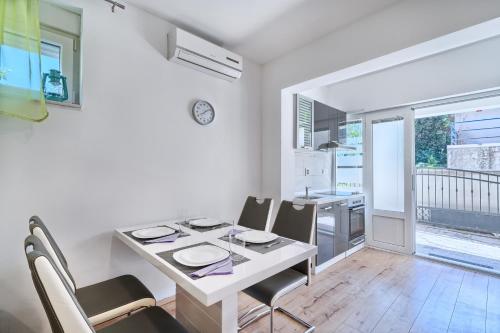 a white dining room with a table and chairs at Apartments Meštrović with heated swiming pool- near Split in Kaštela