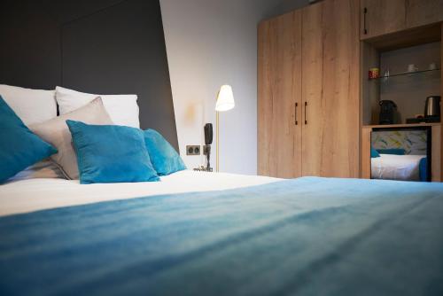 a bedroom with a bed with blue pillows at Pont du Chalon Hôtel and Restaurant in Margès