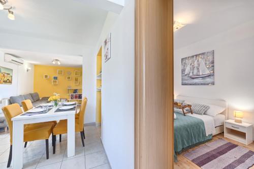 a dining room and living room with a table and a bedroom at Apartments Meštrović with heated swiming pool- near Split in Kaštela