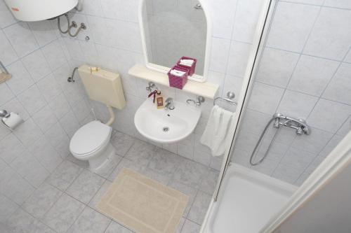 uma casa de banho com um WC, um lavatório e um chuveiro em Apartments Mladen - family friendly & amazing location em Vrsi