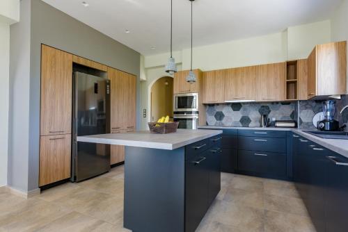 a kitchen with wooden cabinets and a large island at The Leaf House - Kefalonia in Lixouri