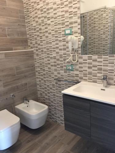 ein Badezimmer mit einem Waschbecken, einem WC und einem Spiegel in der Unterkunft Appartamenti Nadalini in Levico Terme