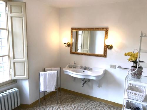 Un baño con un lavabo y un espejo en la pared. en Palazzo Franca, en Montecatini Terme