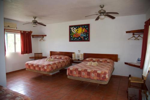 a bedroom with two beds and a ceiling fan at Puerto Lobos Dive camp in Tamiahua