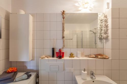 a white tiled bathroom with a sink and a mirror at Apartment Messe, City Toplage in Hannover