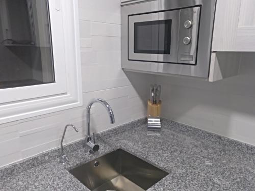a kitchen counter with a sink and a microwave at Luxury CAP SALOU with POOL & BARBECUE & WIFI in Salou