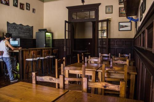 um homem parado num bar num restaurante com mesas e cadeiras em Be King Hostel em Rosário