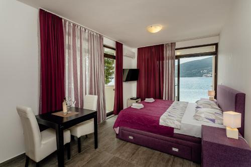 a bedroom with a bed and a desk and a window at Apartments Joy in Herceg-Novi