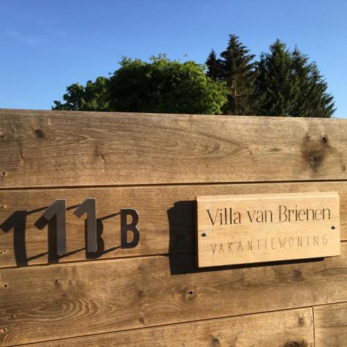 a sign on a wooden fence with trees in the background at Villa van Brienen in Dilsen-Stokkem