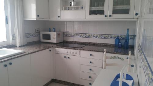 a kitchen with white cabinets and a white microwave at Cedeira playa in Cedeira